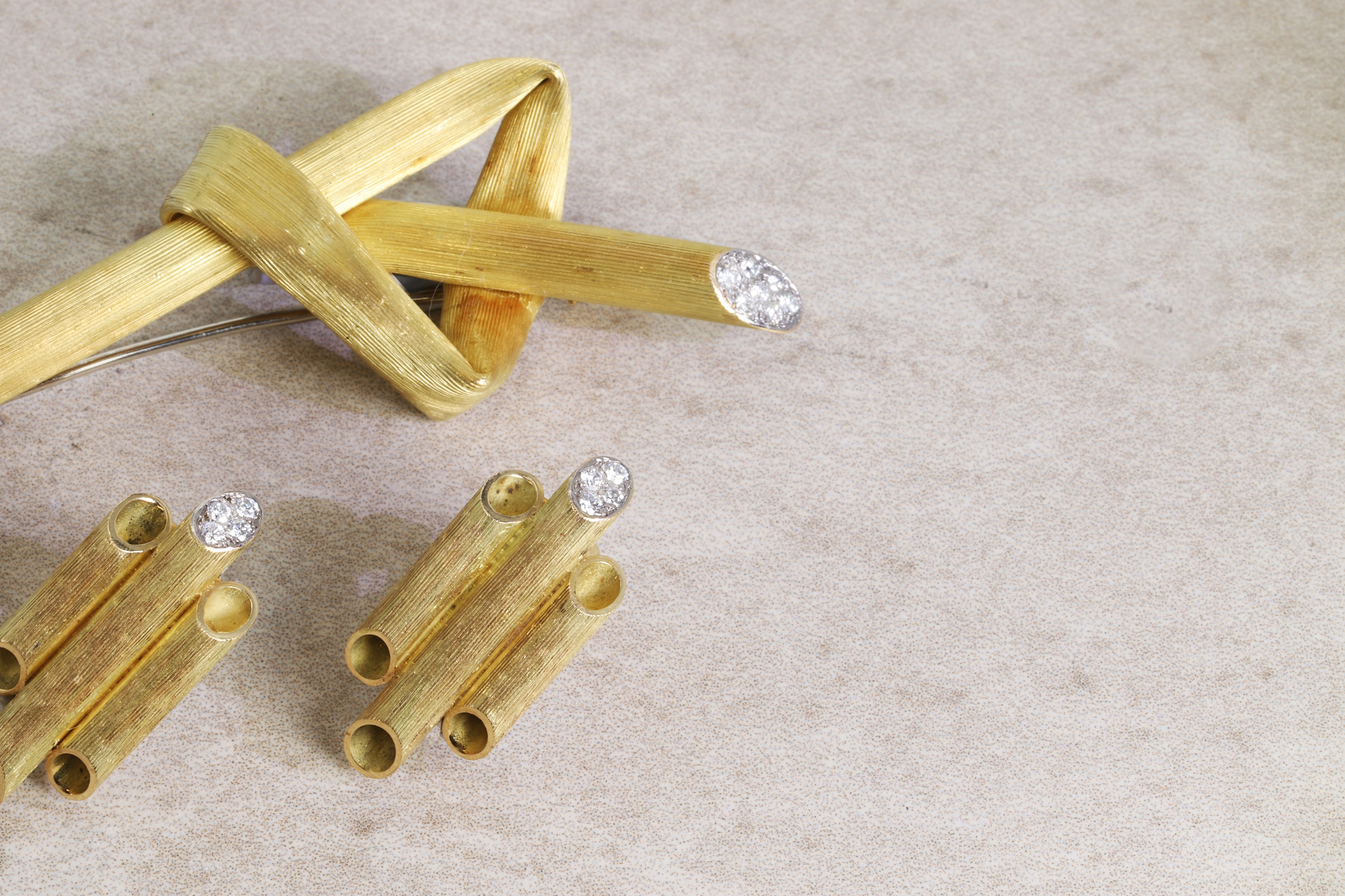 an 18ct gold and diamond brooch, c.1970s, modelled as a stylised straw folded into a knot, in textured gold with pavé diamond terminals (estimate £3,000-5,000), and a pair of 18ct gold and diamond tube earrings